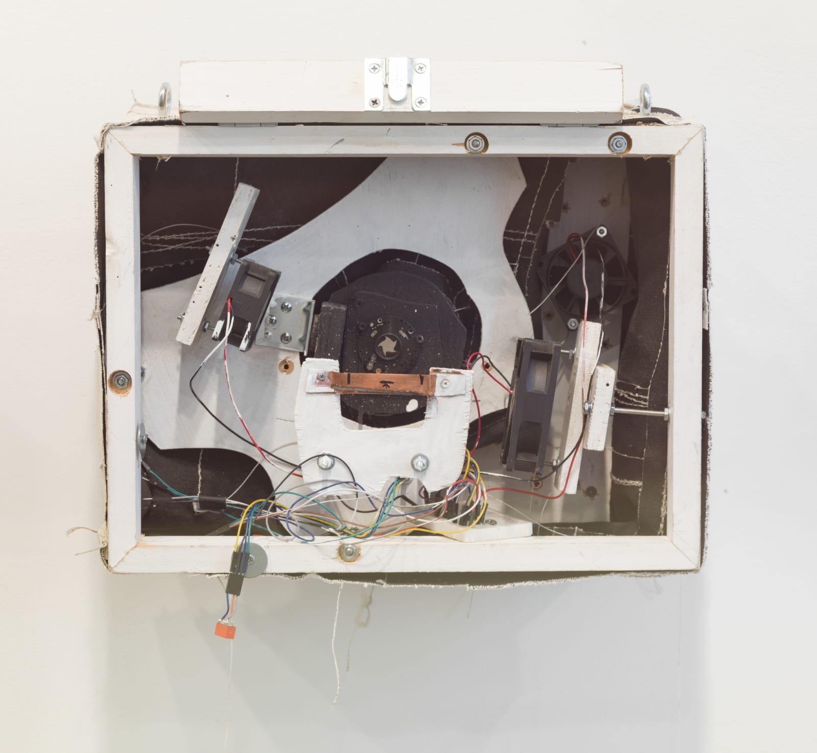 White rectangular sculpture with black designs and wiring inside