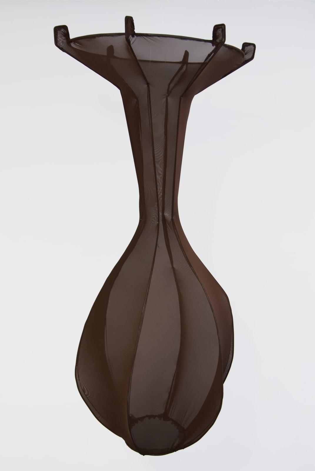 A dark brown, translucent fabric vessel floats in midair