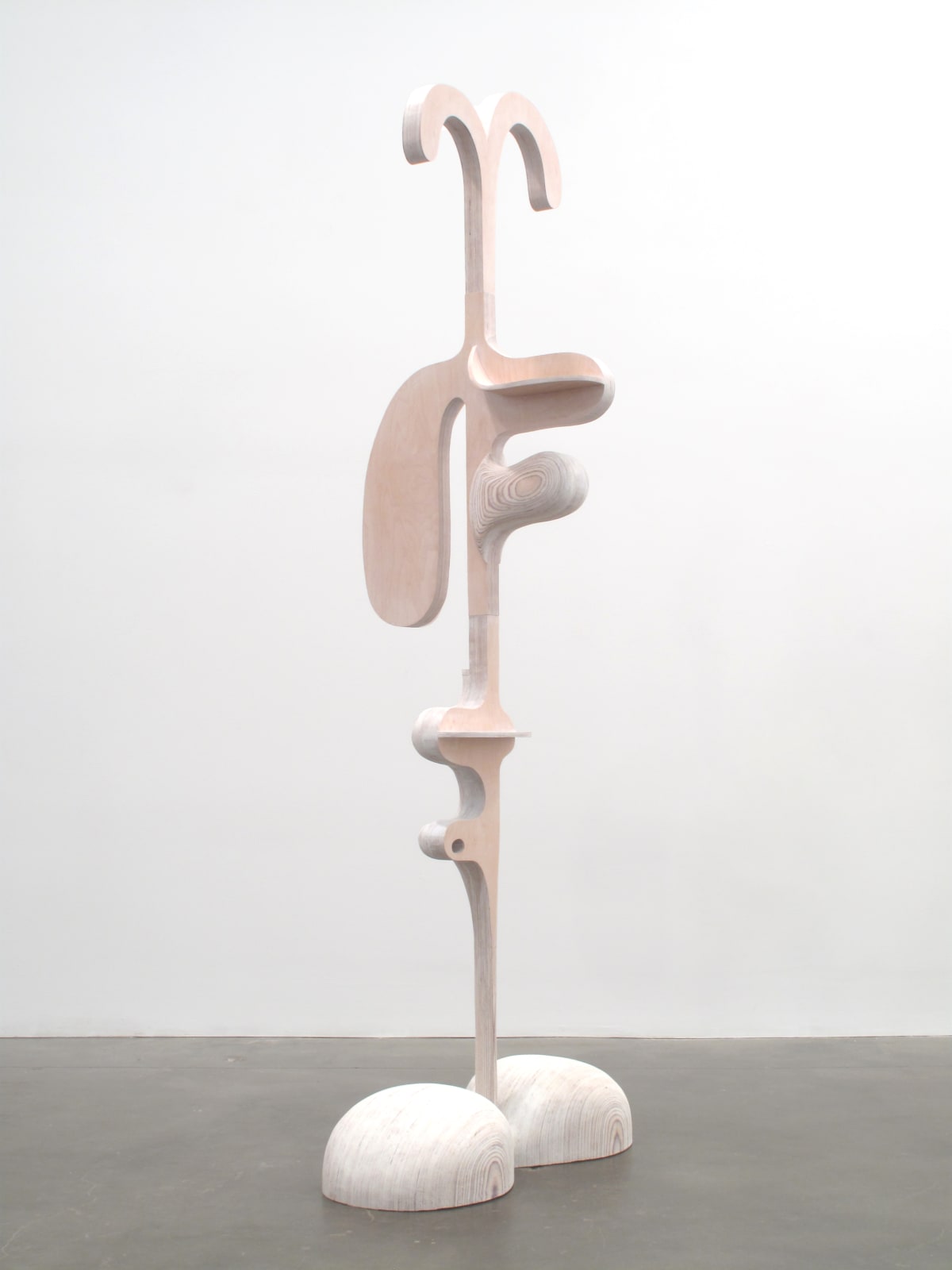 Abstract carved wood sculpture with two feet, and the suggestion of ears and nose