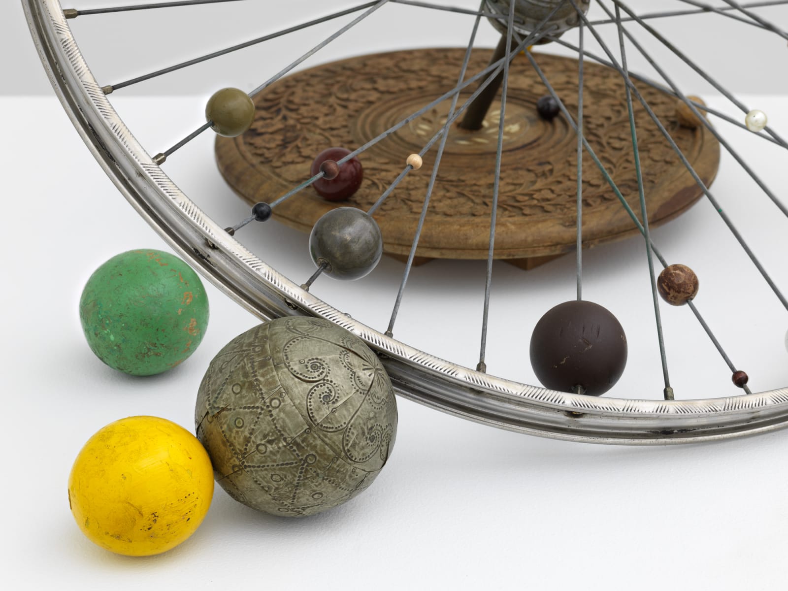 Detail of a bicycle wheel adorned with delicately carved orbs of varying sizes