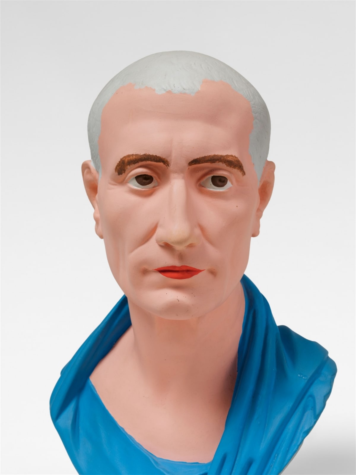 A male bust with no hair and red lips wearing blue