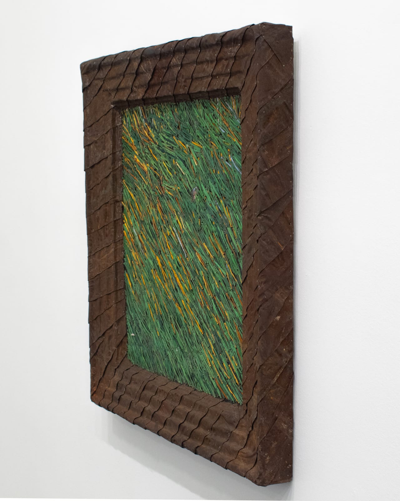 Angle view of green grass made from strips of colored tin in a brown tin frame