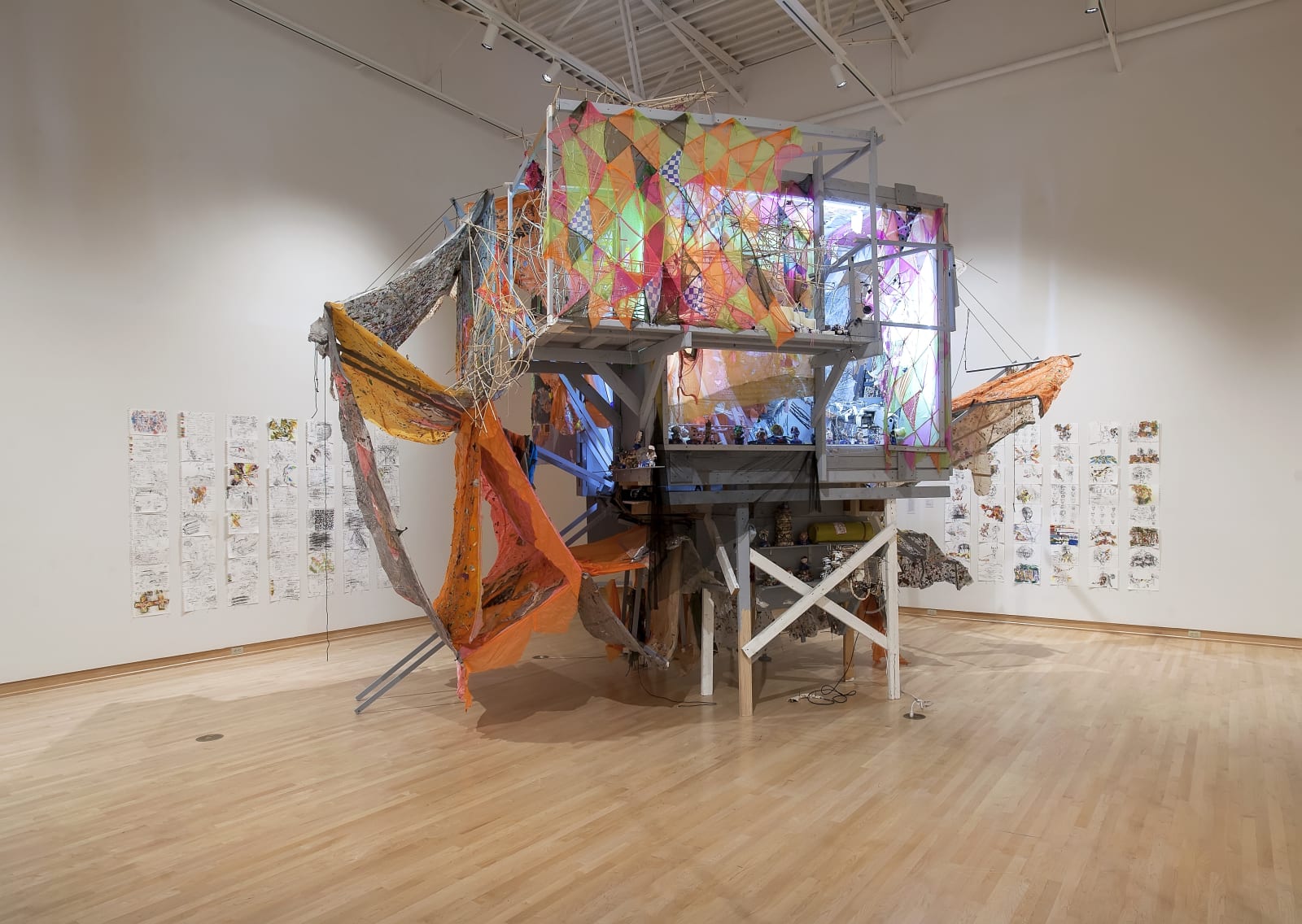 Installation resembling a tree house draped in brightly colored fabrics