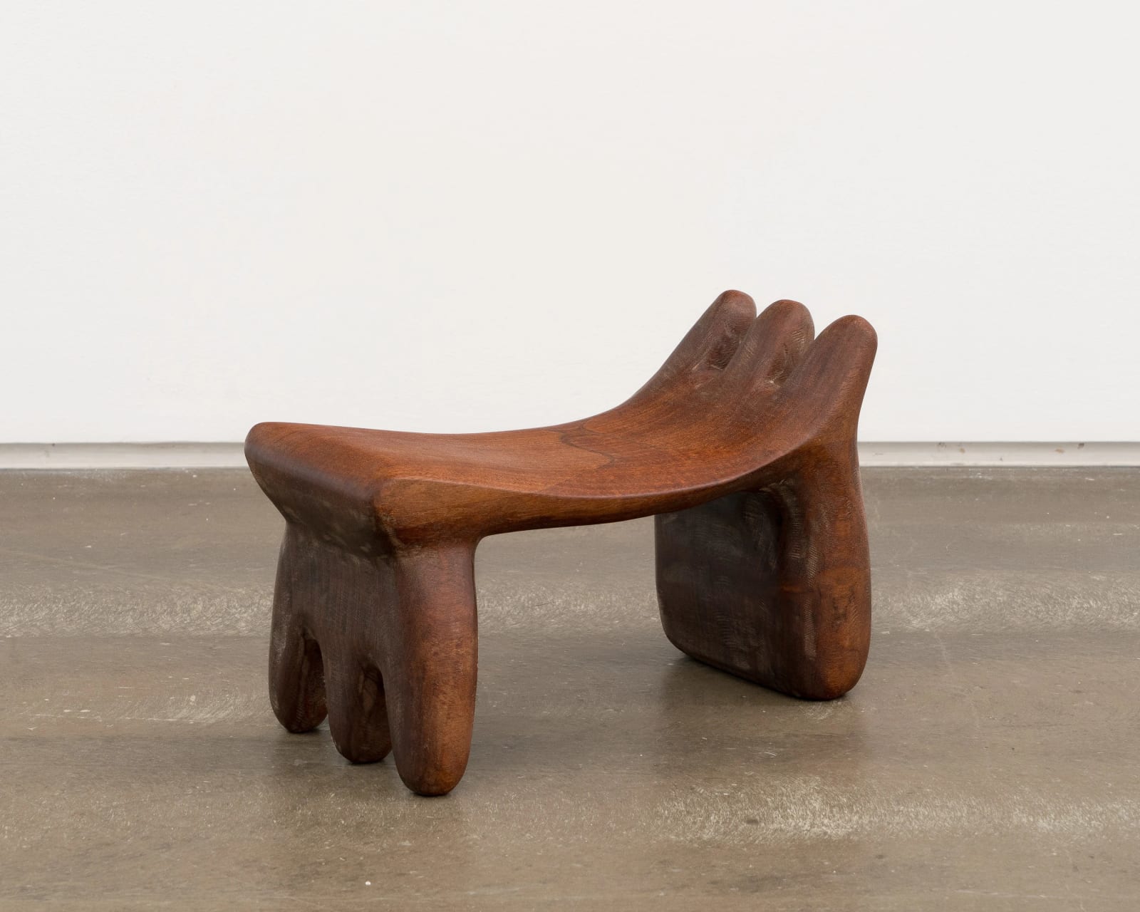 A wooden headrest, one side curving upward and splitting into three rounded segments
