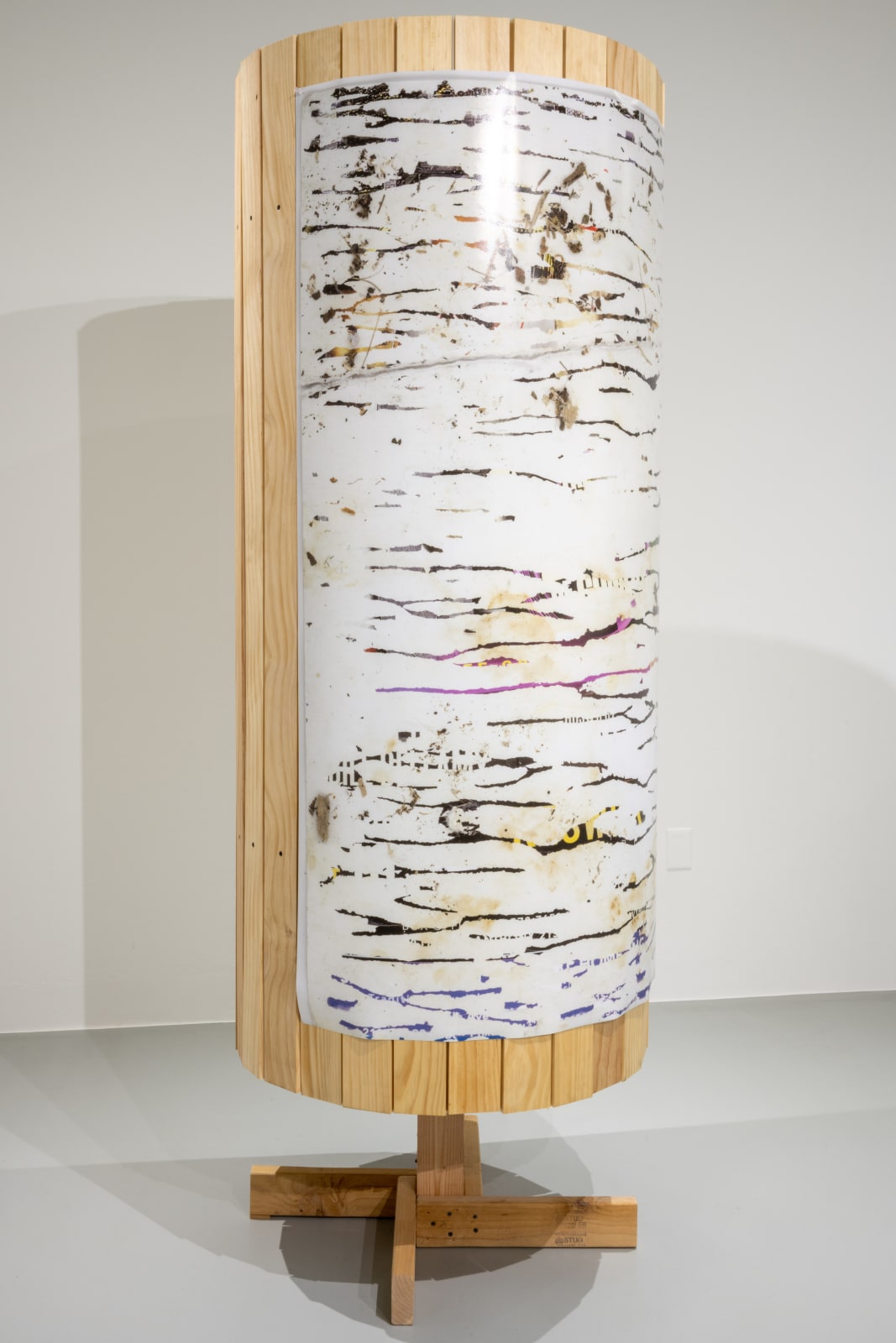 Round free standing wood sculpture with obscured image adhered to the front that appears to be birch bark