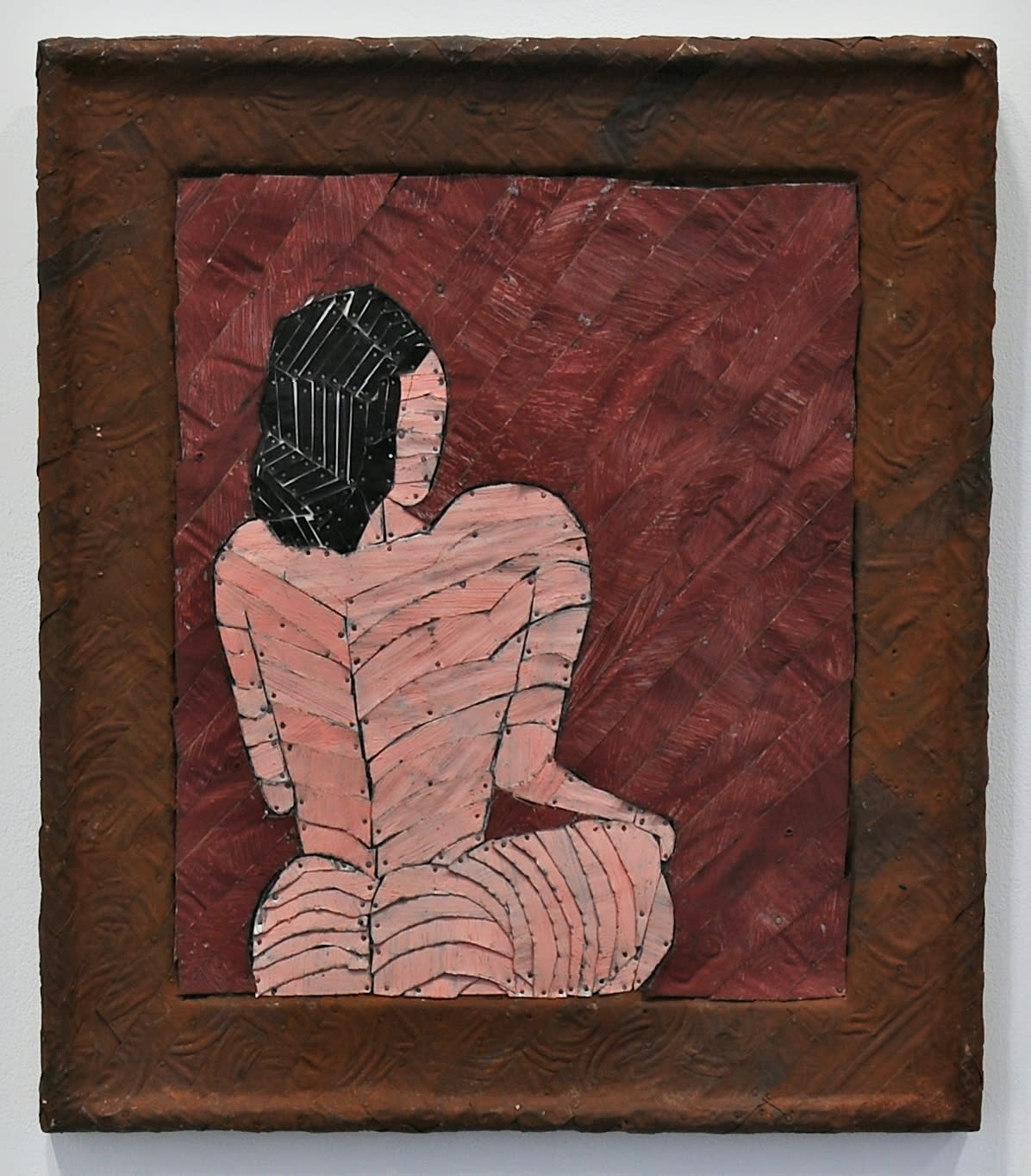 A nude woman sitting in a room made from strips of colored tin