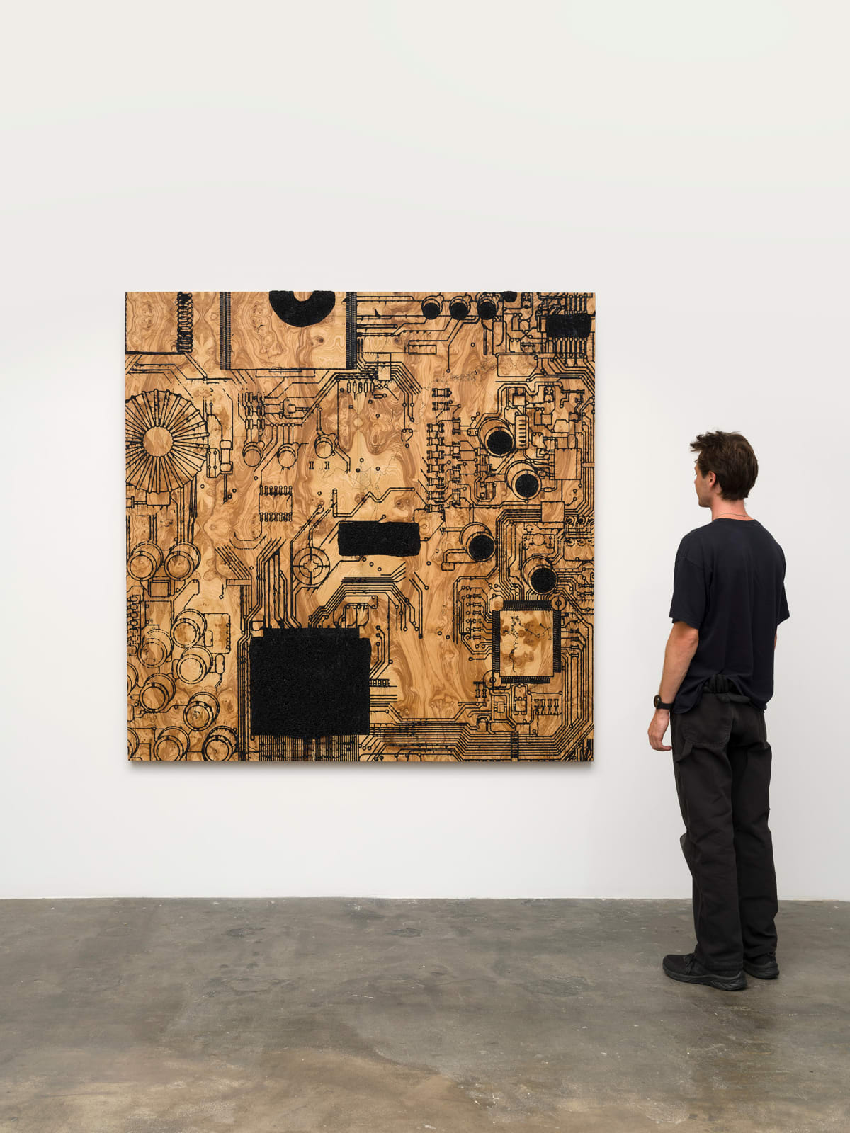 a large wooden sculpture on a white wall with a figure looking at it