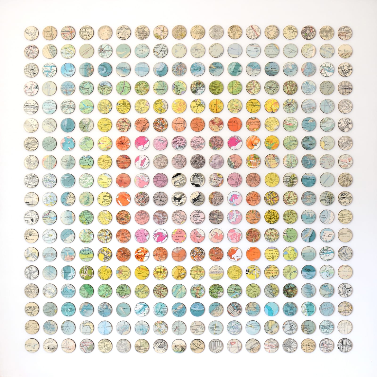 This piece by Amelia Coward arranges circular map fragments from places like London, New York, and Basildon into a vibrant colour gradient, blending geography and abstraction in a striking, structured composition.