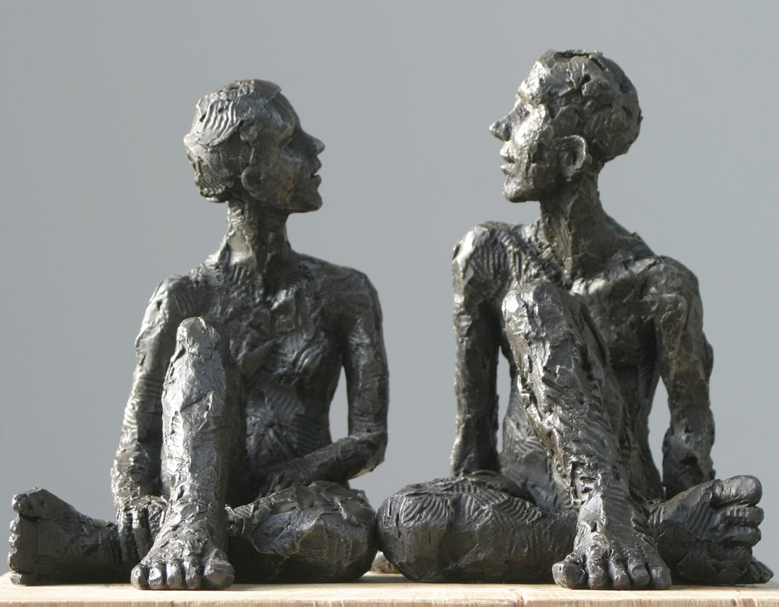 Seated male & female iron resin sculptures