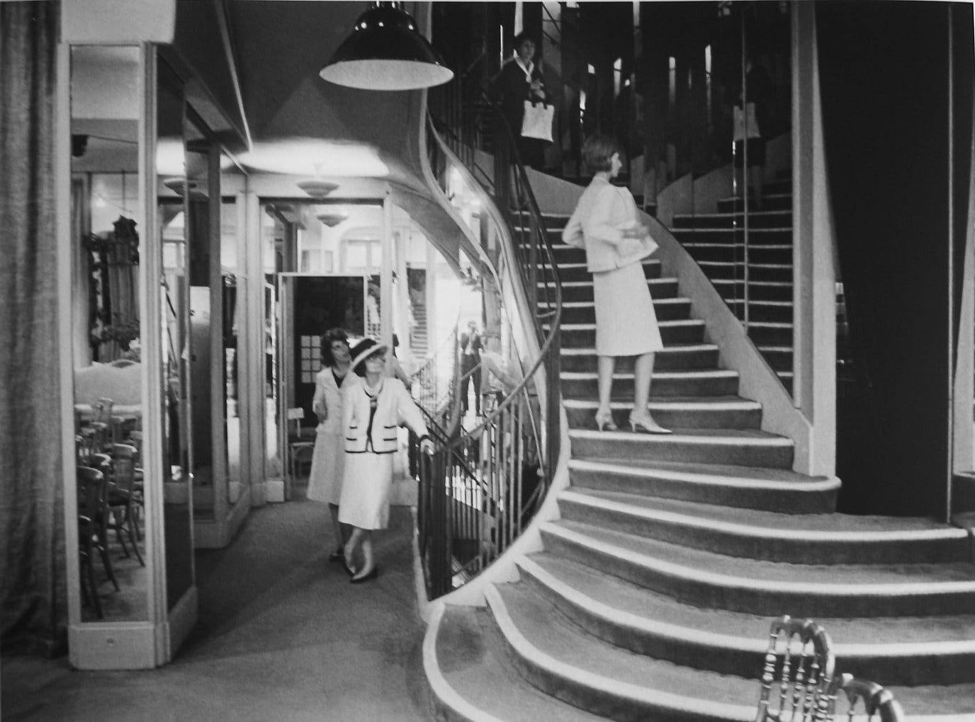 Black and white photograph of Designer Coco Chanel next to her staircase in the House of Chanel, Paris