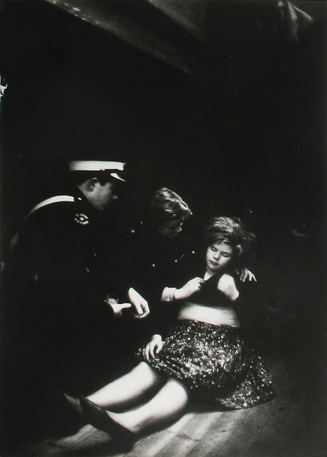Black and white photograph of a woman who has just fainted and being helped by cops at a Beatles show, a result of “Beatlemania”