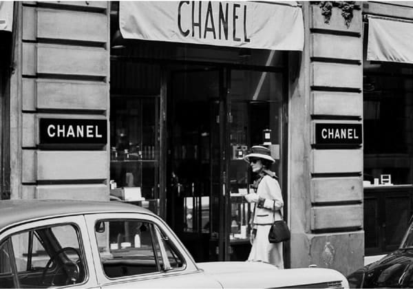 Black and white photograph of Coco Chanel walking on rue Cambon from her apartment at the Hôtel Ritz to the House of Chanel, Paris