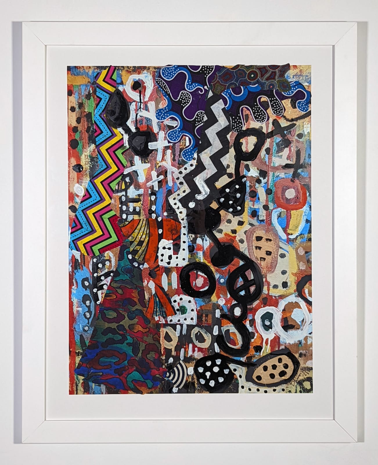 White framed colorful artwork comprised of oil and patterned fabric on print in a