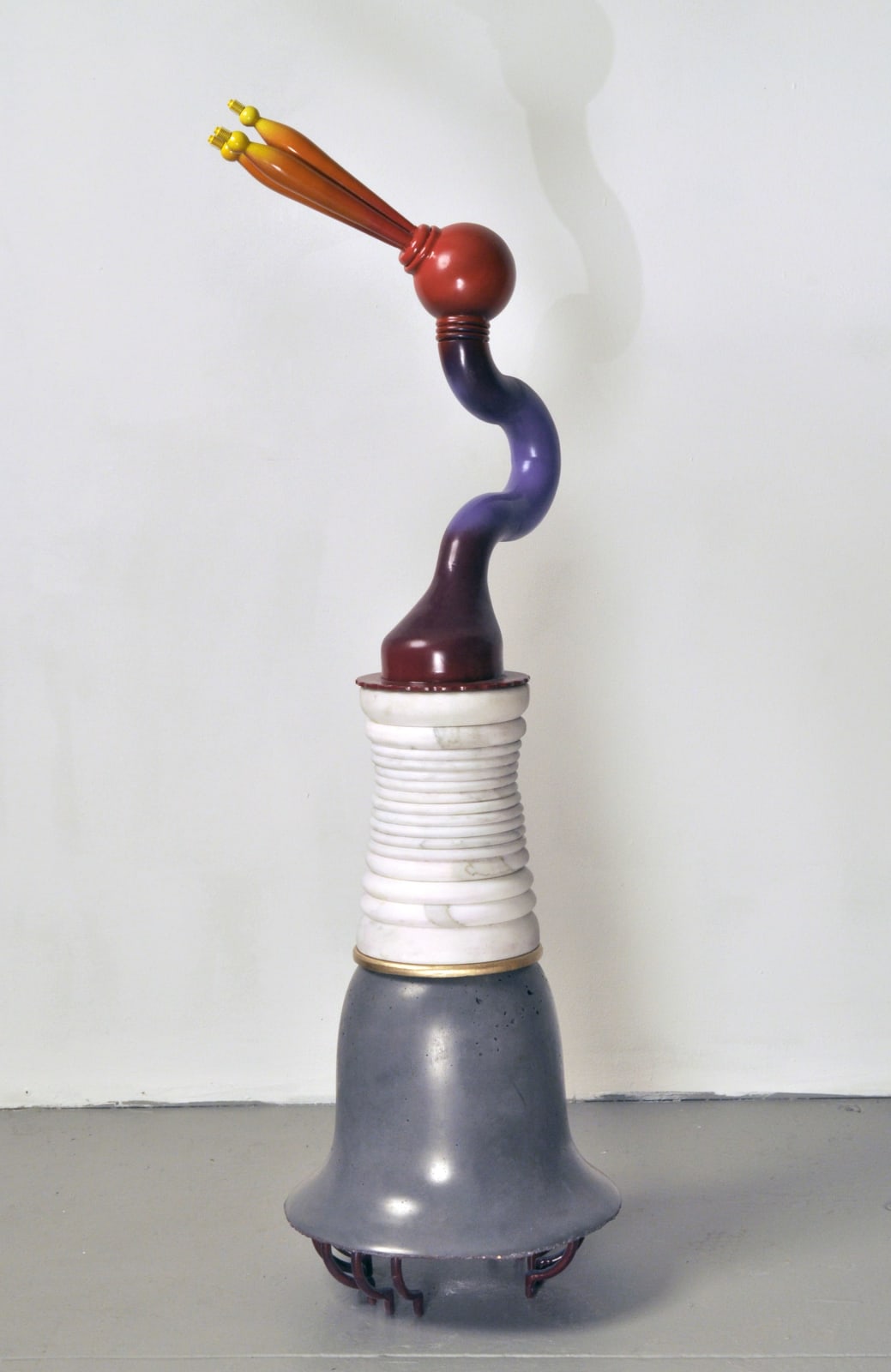 Sculpture with a grey base, layered white piece, and a curved glass piece that fades blue, red, and orange