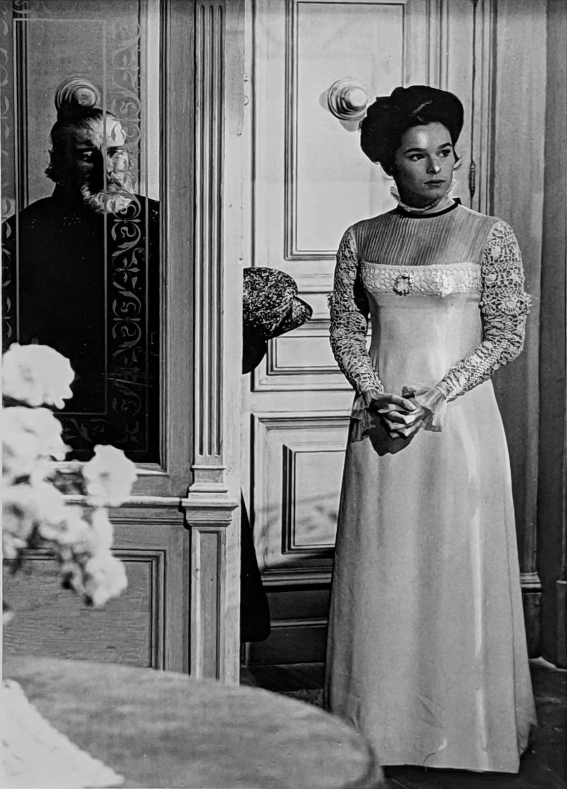Black and white photograph of Geraldine Chaplin in the role of Tonya, wearing a long white wedding dress, preparing for a scene set up pre-Russian Revolution, on the set of “Doctor Zhivago”