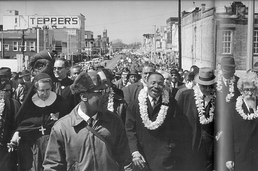 Black and white photograph of Dr. Martin Luther King Jr. leading the march cross the Edmund Pettus bridge in Selma, Alabama