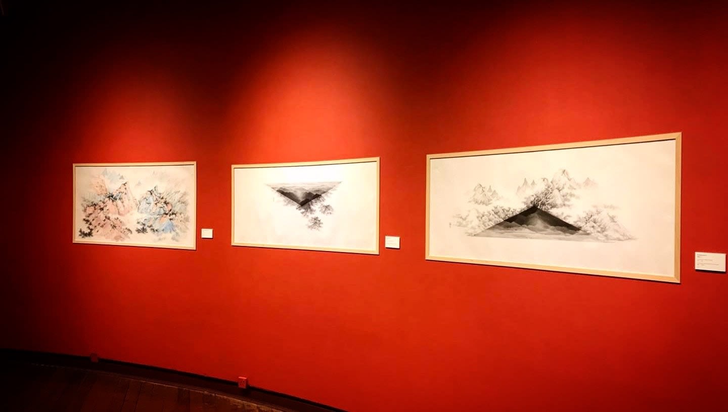A group of paintings on a red wall