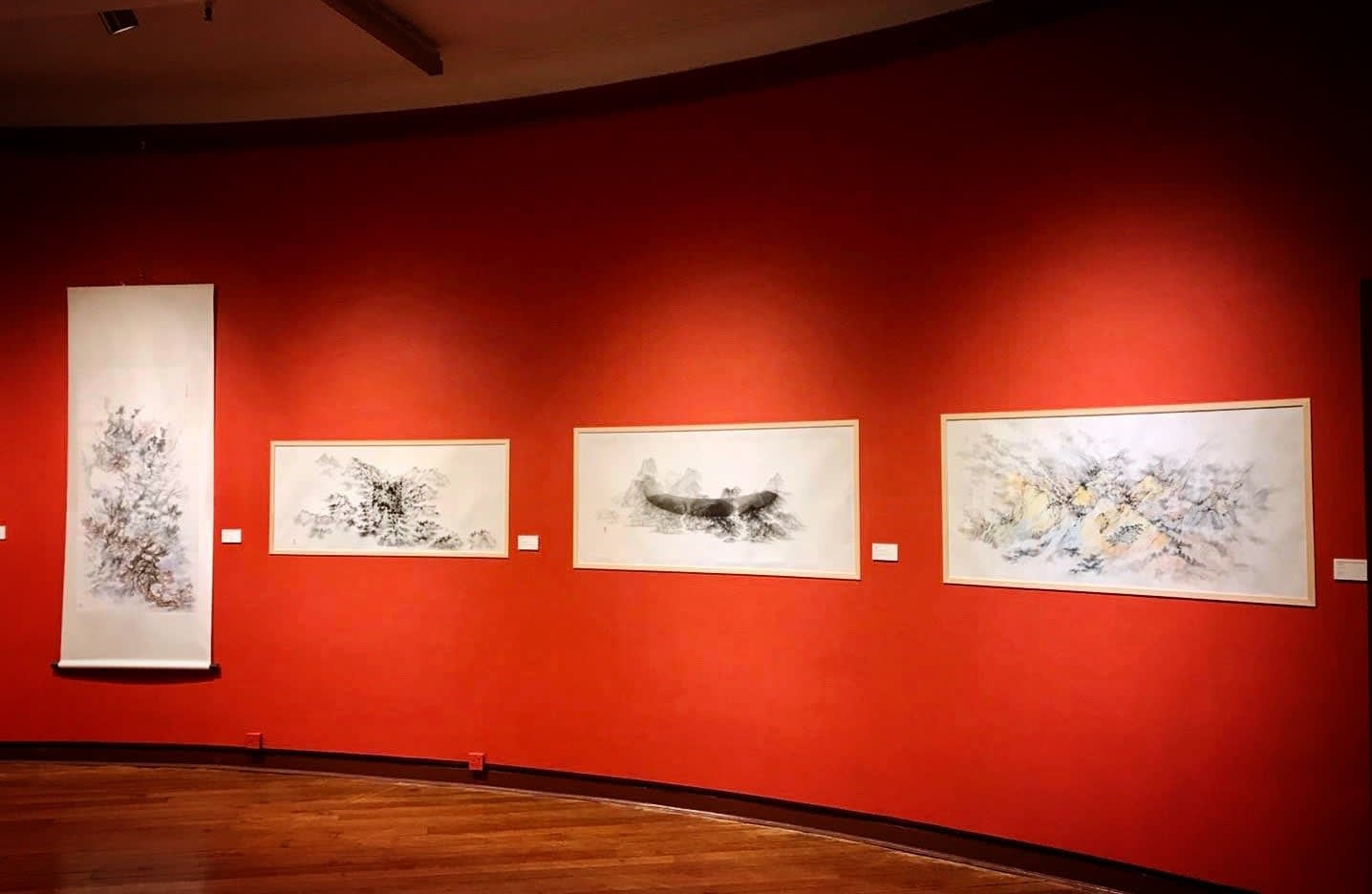 A group of paintings on a red wall