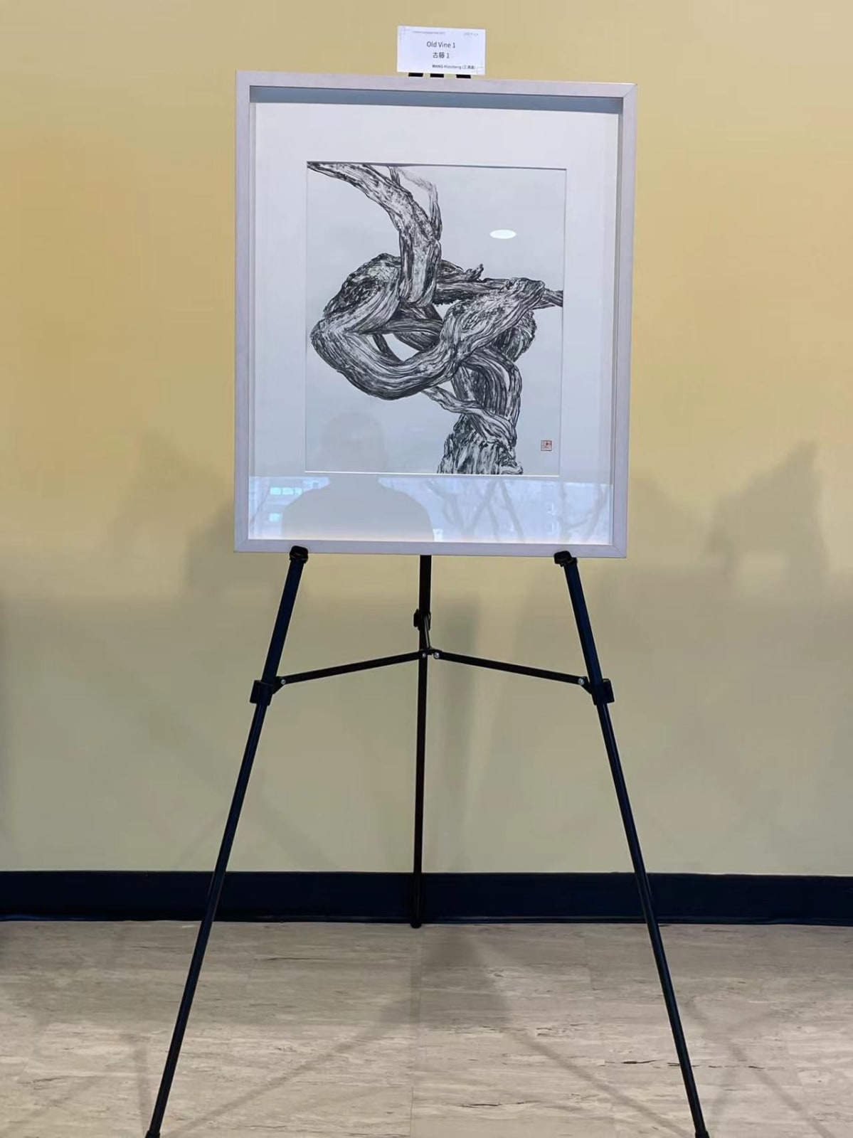an artwork with black cirrus depicted on a piece of white paper, exhibiting on a tripod stand
