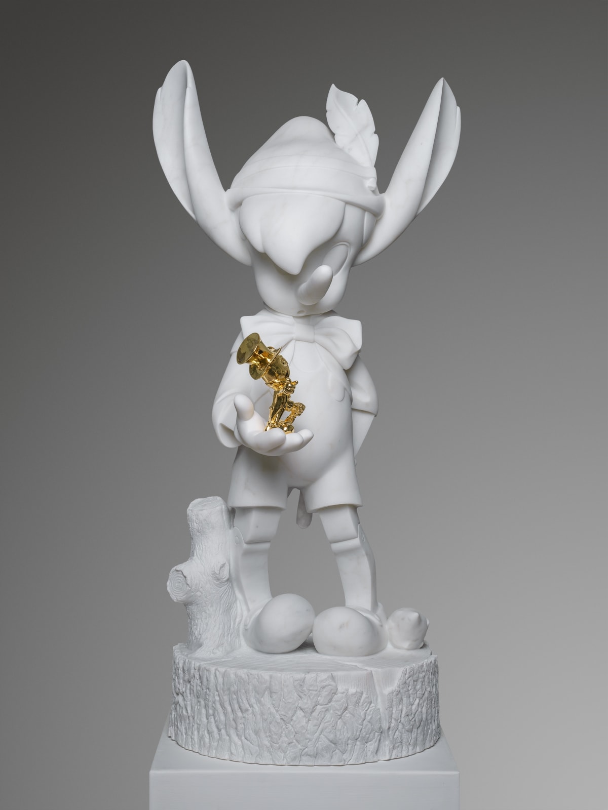 Marble sculpture featuring a pinocchio with a gold cricket, part of the 'Cartoon' series by artist Filippo Tincolini view from the front