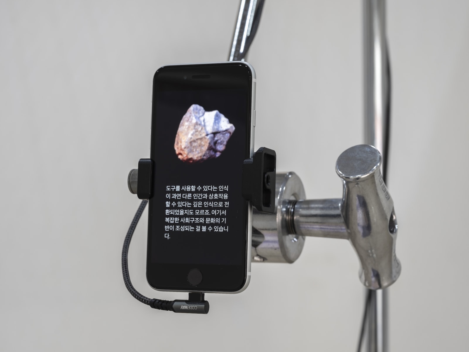 Detail: Daisy-Chain-Agora, 2023, iPhone, steel stand, grip head with arm, charger, cable, adhesive PVC sheet, dimensions variable, 5-channel video, 27min(loop), color, sound, AI model(GPT-4, Stable Diffusion), Curtesy Hong Cheol Gi