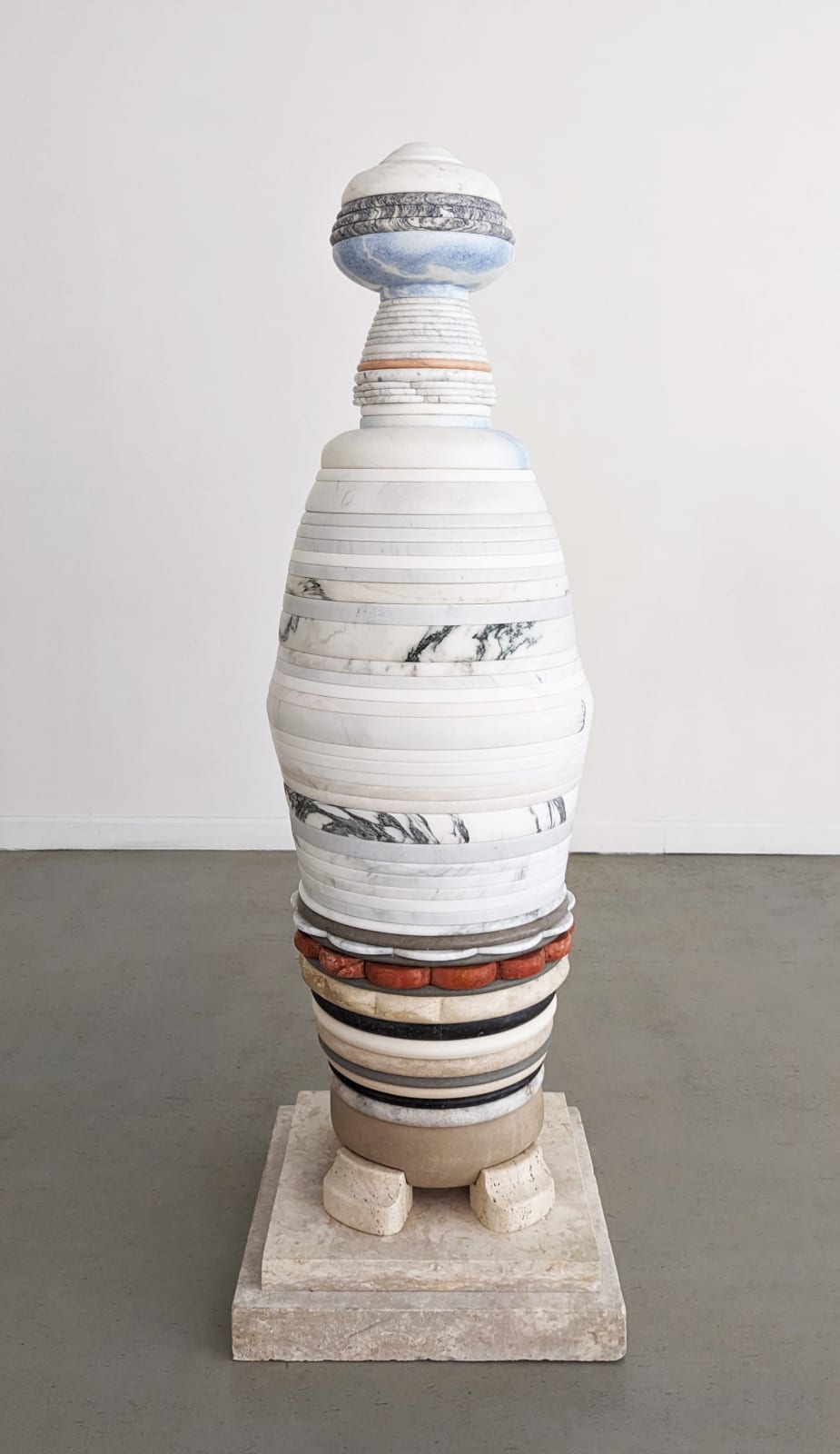 Minimalist sculpture comprised of layers of light-colored marble in a gallery setting