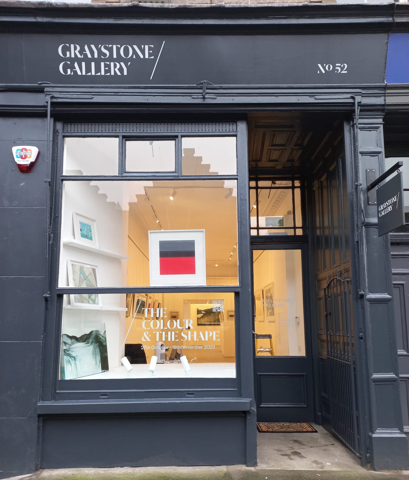 Exterior of Graystone Gallery in Stockbridge, Edinburgh, featuring a stylish black facade with large windows displaying framed artwork and a sign reading "The Colour & The Shape.