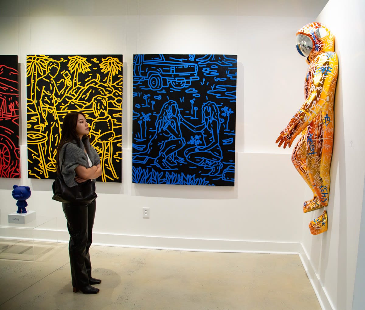 Woman staring at paintings and sculpture displayed at Carousel Fine Art's new gallery space in Buckhead Village, Atlanta during an event for their grand opening.
