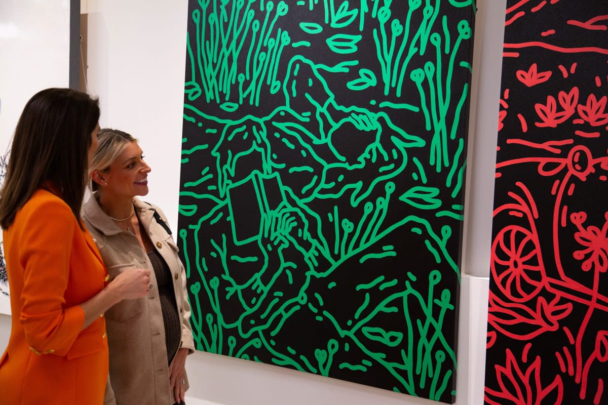 People staring at paintings displayed at Carousel Fine Art's new gallery space in Buckhead Village, Atlanta during an event for their grand opening.