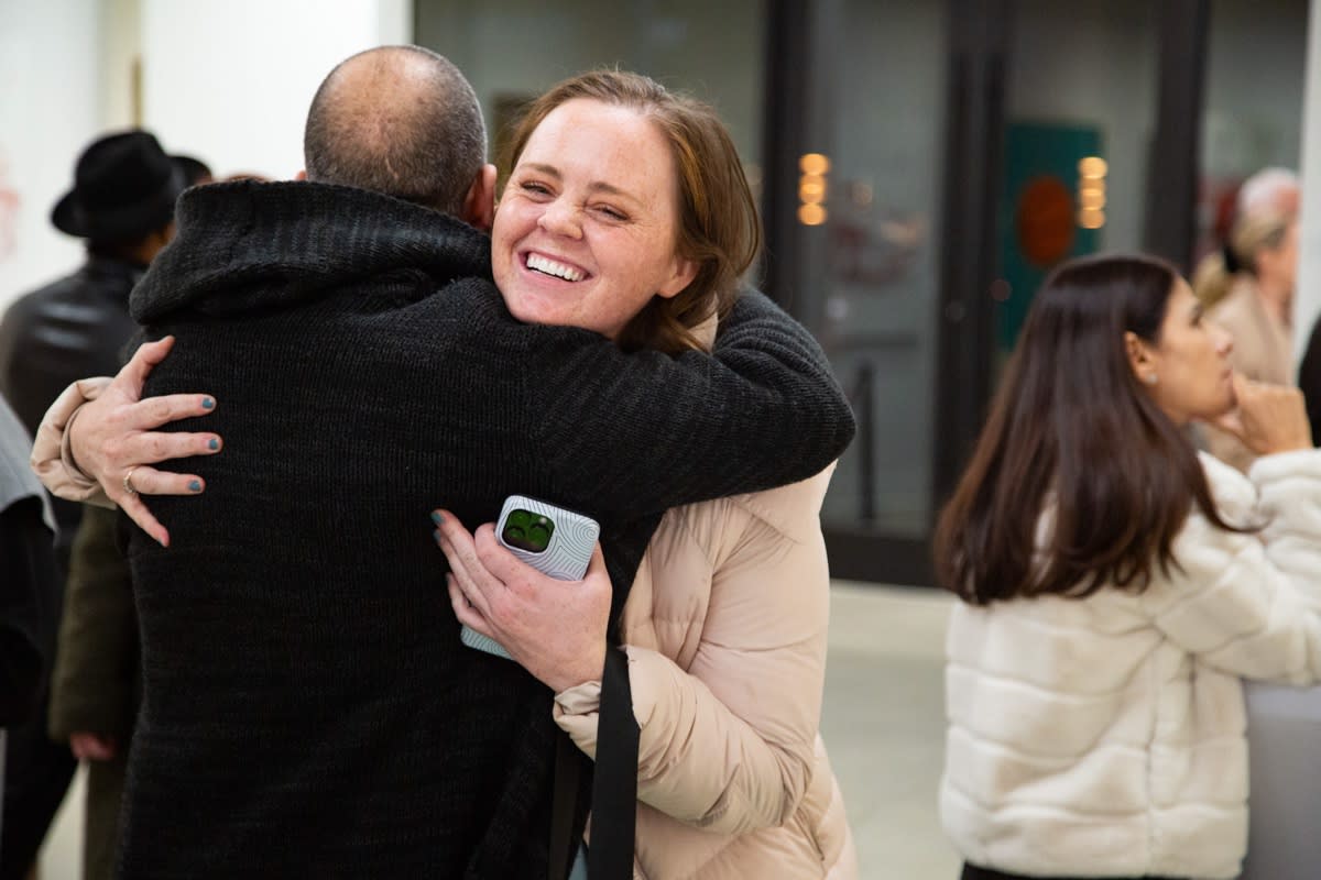 People hugging at Carousel Fine Art's new gallery space in Buckhead Village, Atlanta during an event for their grand opening.