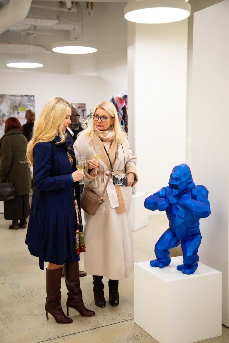 People staring at paintings and sculpture displayed at Carousel Fine Art's new gallery space in Buckhead Village, Atlanta during an event for their grand opening.