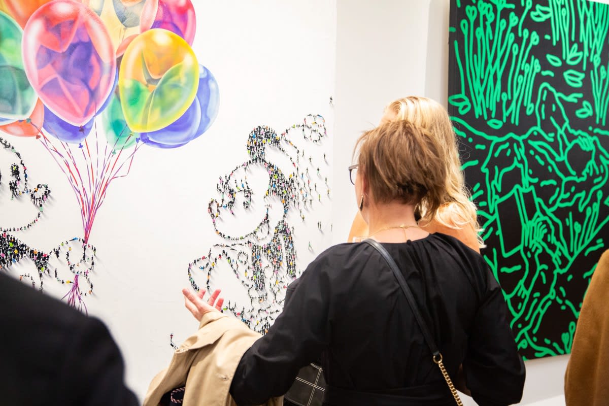 People staring at paintings displayed at Carousel Fine Art's new gallery space in Buckhead Village, Atlanta during an event for their grand opening.
