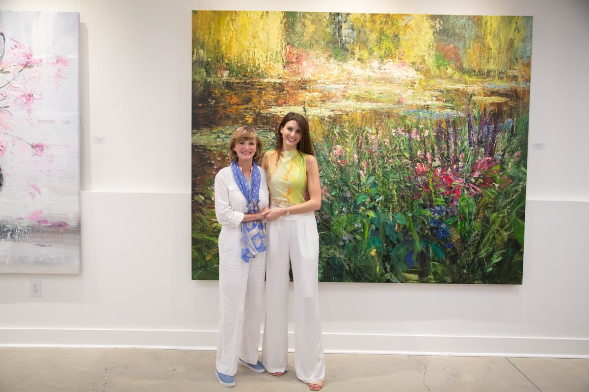 People posing in front of Eric Alfaro's paintings displayed in Carousel Fine Art's Buckhead Village location during the Eric Alfaro exhibition "Spring Reverie."