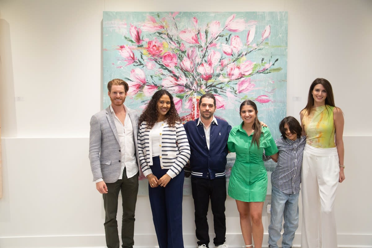 People posing in front of Eric Alfaro's paintings displayed in Carousel Fine Art's Buckhead Village location during the Eric Alfaro exhibition "Spring Reverie."