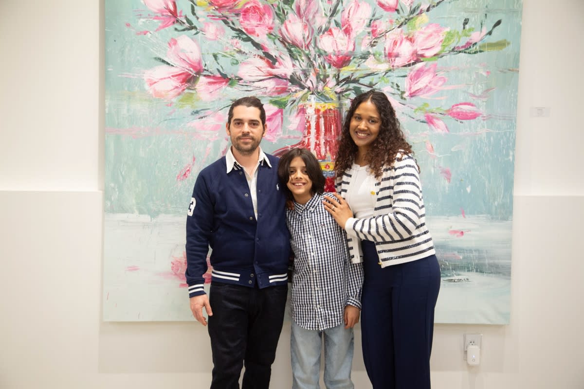 People posing in front of Eric Alfaro's paintings displayed in Carousel Fine Art's Buckhead Village location during the Eric Alfaro exhibition "Spring Reverie."