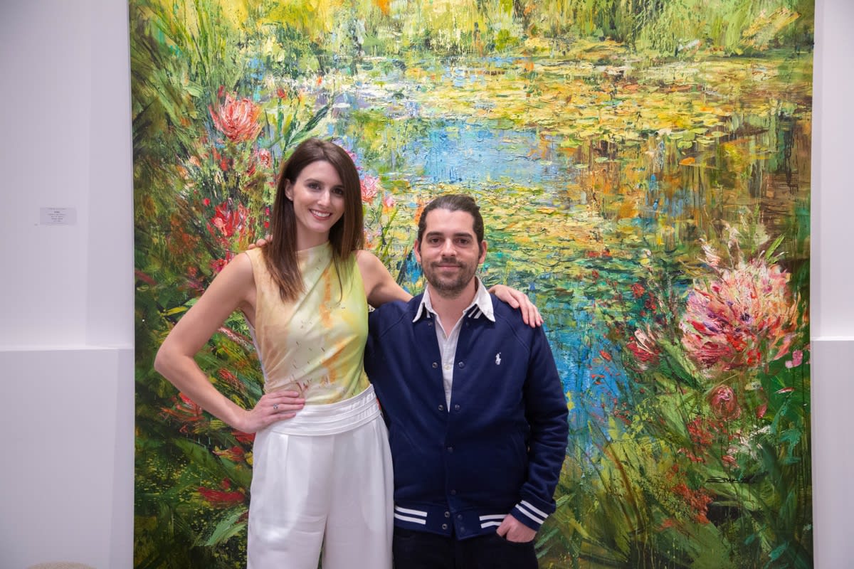 Gallery owner of Carousel Fine Art and artist Eric Alfaro posing in front of Eric Alfaro's paintings displayed in Carousel Fine Art's Buckhead Village location during the Eric Alfaro exhibition "Spring Reverie."