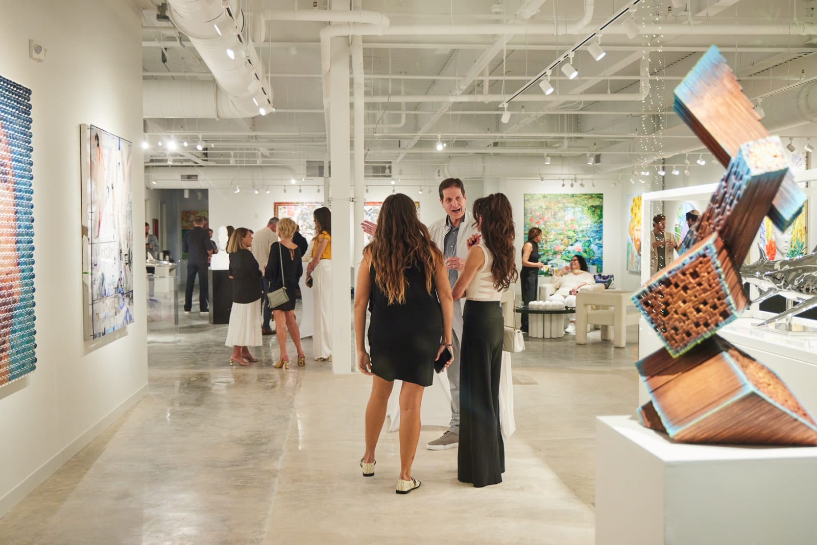 Panoramic view of packed West Palm Beach NORA gallery with collectors exploring contemporary artworks on every wall.