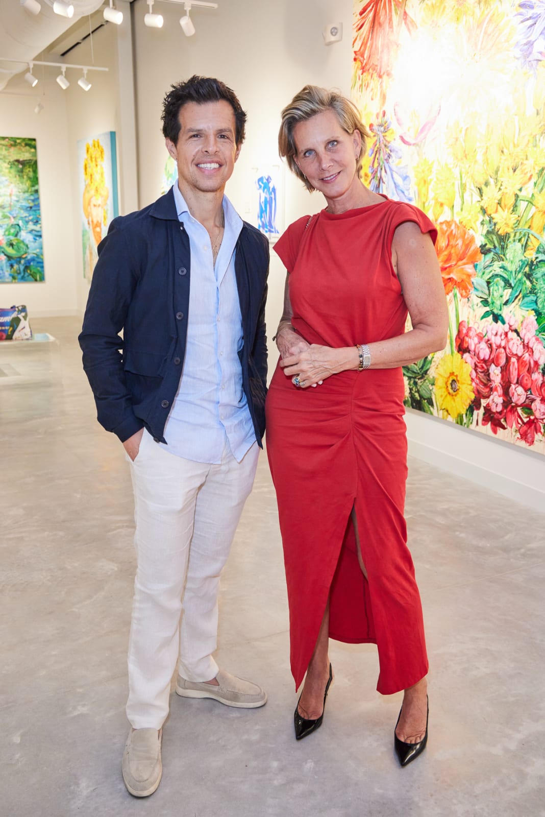 Collector couple having a great time at opening event and posing in front of Eric Alfaro wild flower piece.