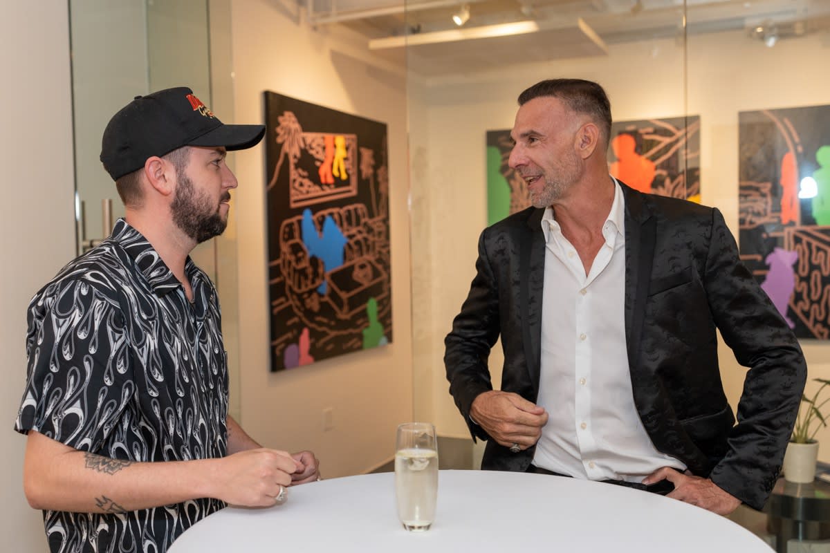 Men talking at Carousel Fine Art's gallery space in Miami, FL during Chance Cooper's Spotlight Exhibition, "Between Me and You."