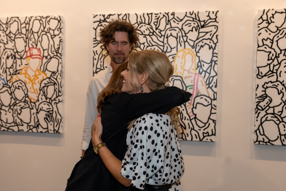 People hugging at Carousel Fine Art's gallery space in Miami, FL during Chance Cooper's Spotlight Exhibition, "Between Me and You."