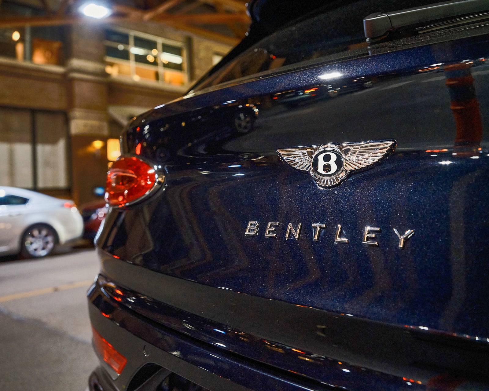 Close-up of Rolls-Royce rear logo with gallery signage blurred behind in River North Chicago.
