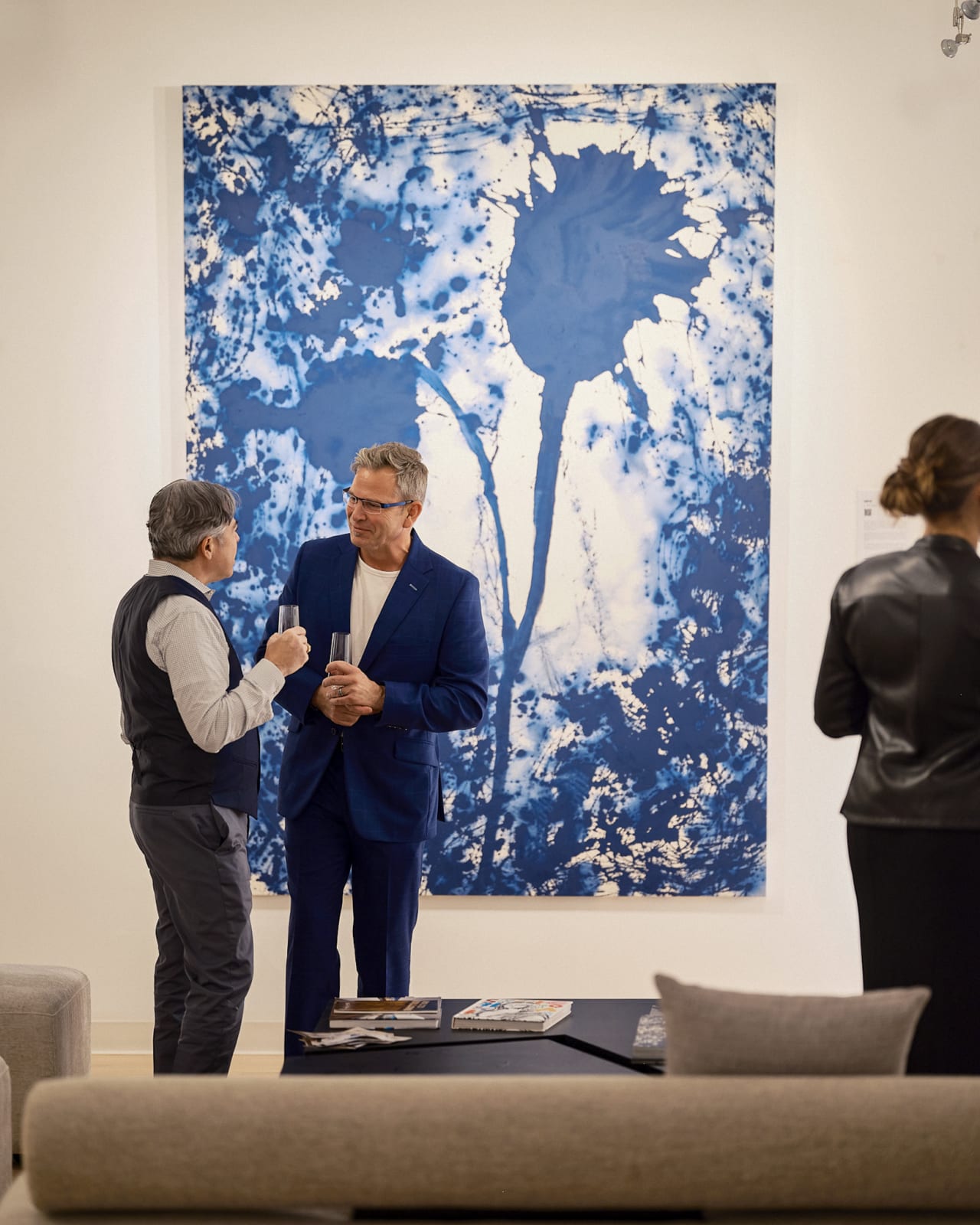 Collector studying Jason M. Peterson street photograph while Jorge Luis Santos large-scale abstract glows behind at Chicago event.