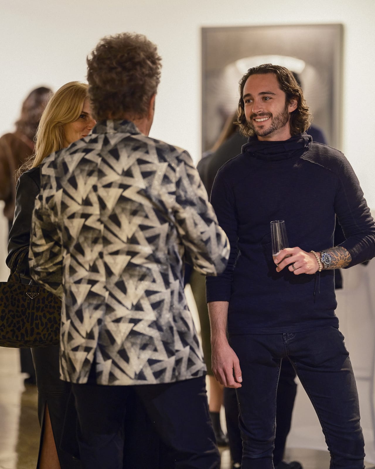 Two guests discussing favorite Jason M. Peterson piece while smiling and gesturing with glasses in hand.