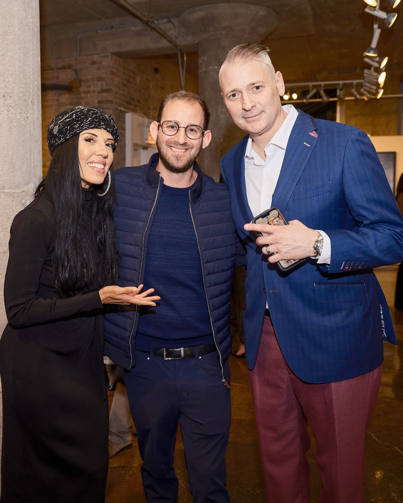 Small group posing with gallery advisors under Jason M. Peterson feature wall during Chicago luxury reception.