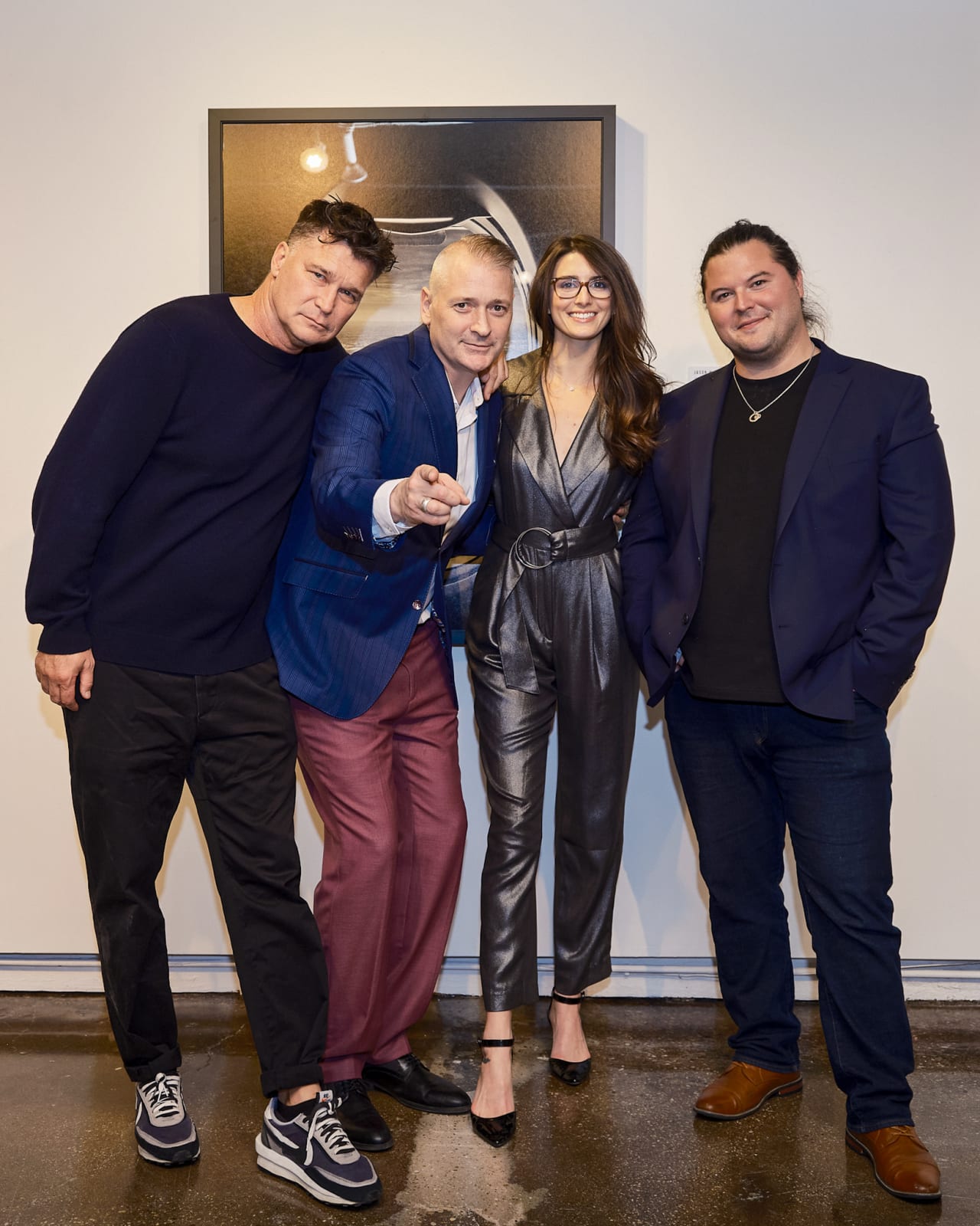 Four advisors posing arm in arm in front of a wall of Jason M. Peterson monochrome architectural photographs.