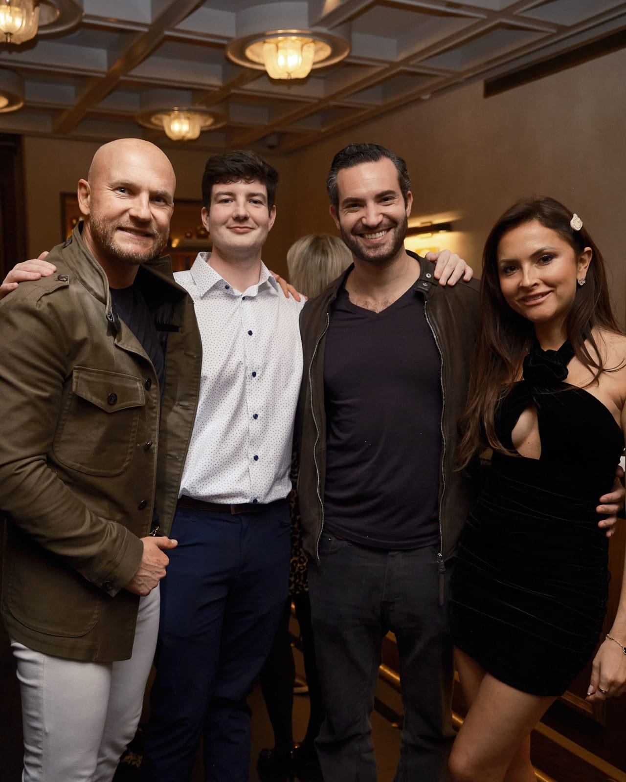 VIP guests posing with gallery director in front of Jason M. Peterson feature wall at Chicago luxury photography event.