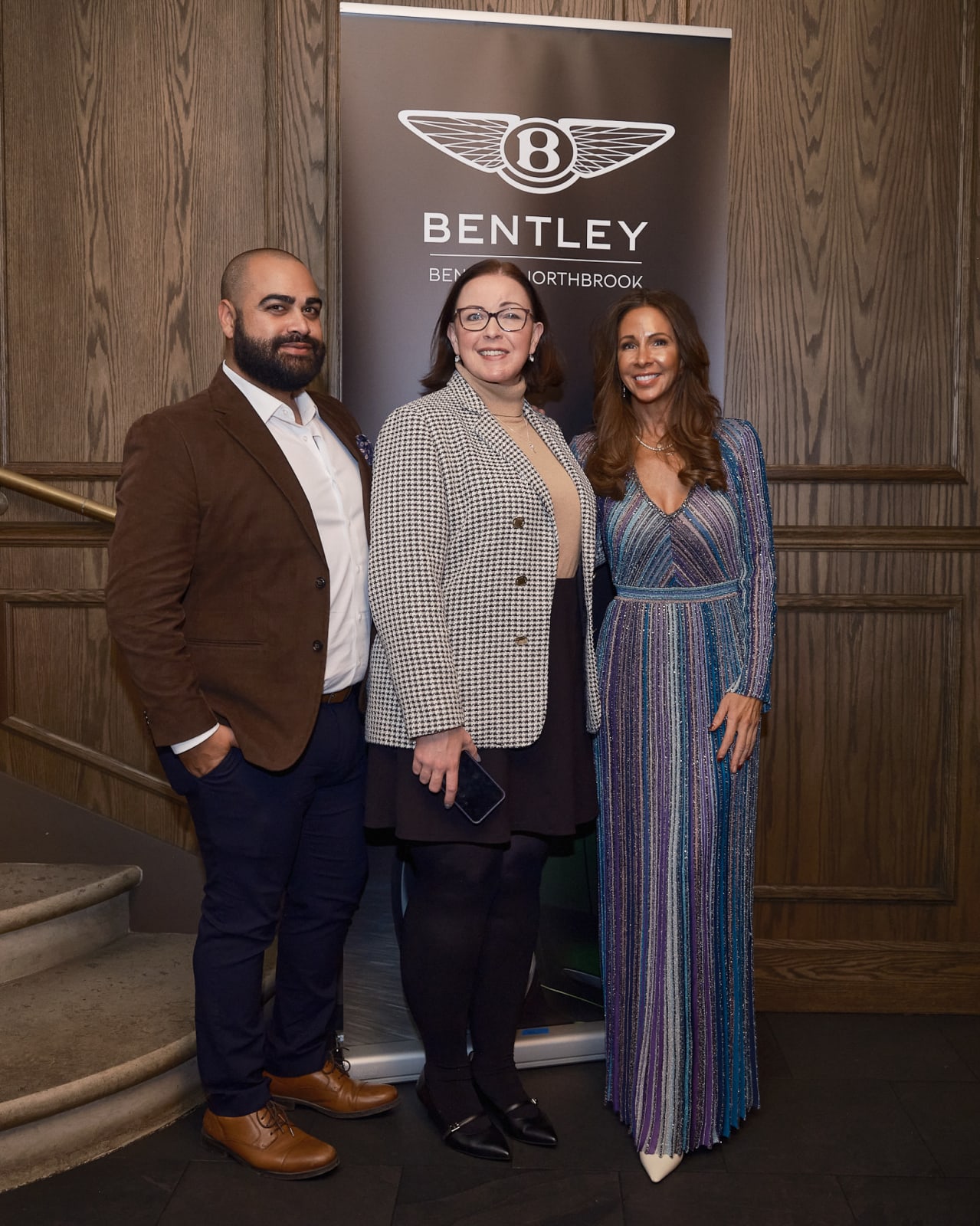 Real estate agents posing between two Bentley cars outside Jason M. Peterson photography spotlight.