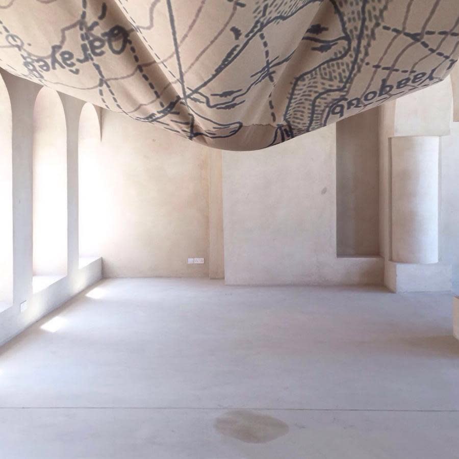 PORTRAIT OF A LAKE 2017, print on natural fabric (300x400cm), hemp strings, 3L of water produced by a nearby dehumidifier, poured every day Installation view from Sharjah Biennial 13 Tamawuj, curated by Christine Tohme, Sharjah, UAE Portrait of a Lake consists in a suspended piece of map. It shows us the outlines of a lake and its surrounding grounds, now hanging above us. As water pours on it, the representation of the lake, dating back from 1938, becomes humid again; the lake is reactivated. As it crosses the representation of the lake, water becomes water from the lake. Dripping down onto the floor, it slowly draws the outlines of the lake anew; A self-portrait, drawn by the lake itself. The portrayed lake is Yammoune – Little Sea (from Ugaritic, "yam"). On its West shore are scattered the ruins of a Roman sanctuary. Dedicated to Astarte-Venus, goddess of fertility, the sanctuary also held statues of shepherd-gods protecting pastoral life and agriculture. Built next to Nabaa el-Arbain, the main spring flowing into the lake, the sanctuary had a direct connection with water and purification rituals. Abundant with water from the spring at snowmelt, Yammoune Lake progressively empties, until the end of summer, forming a fertile depression. Culminating above the fertile valley of the Bekaa, which it partly irrigates, its water also irrigates the illegal crops cultivated in the village of Yammoune. Situated on the Levant geological fault, marking the boundary between the eastern Mediterranean and the Arabian plates, Yammoune Lake is a “pull-apart”: a void constituted by the slippage of the two tectonic plates. The fault, departing from Jordan, crosses Lebanon’s entire geography, as well as Israel and Syria, before ending in Turkey; Divided insegments, breaking one by one, at different times, it is responsible for a significant amount of seismic events in the Middle-East. Closely following the nature, cycle and history of the lake, the installation is also reminiscent of a sail, a tent or a breast.