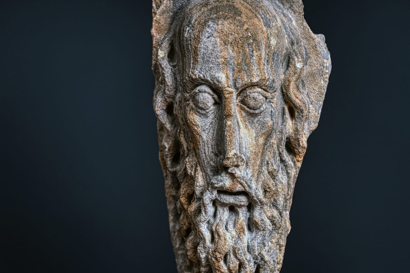 A CARVED STONE HEAD OF A BEARED MAN
