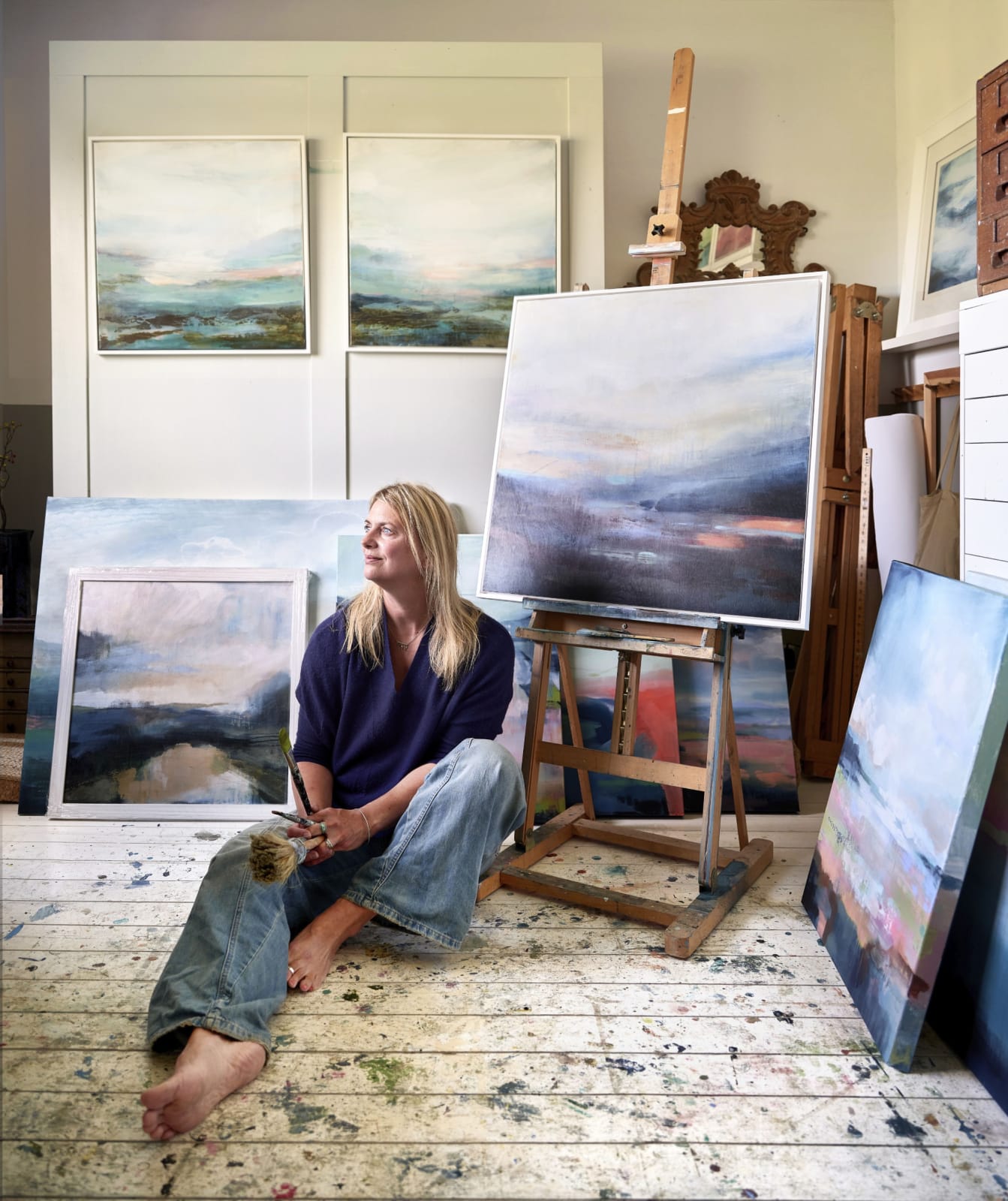 Miranda Carter, captured in her studio surrounded by canvases and brushes, reflecting on the intersection of art and sustainability. Photography rights to Miranda Carter, 2025. Copyright © 2025 Les Bois Magazine. All rights reserved.